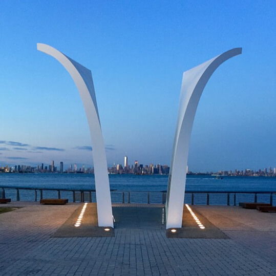 Two curved white arches frame a distant city skyline by the water.