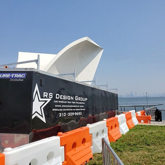 Construction site with safety barriers and a design group banner under clear skies.